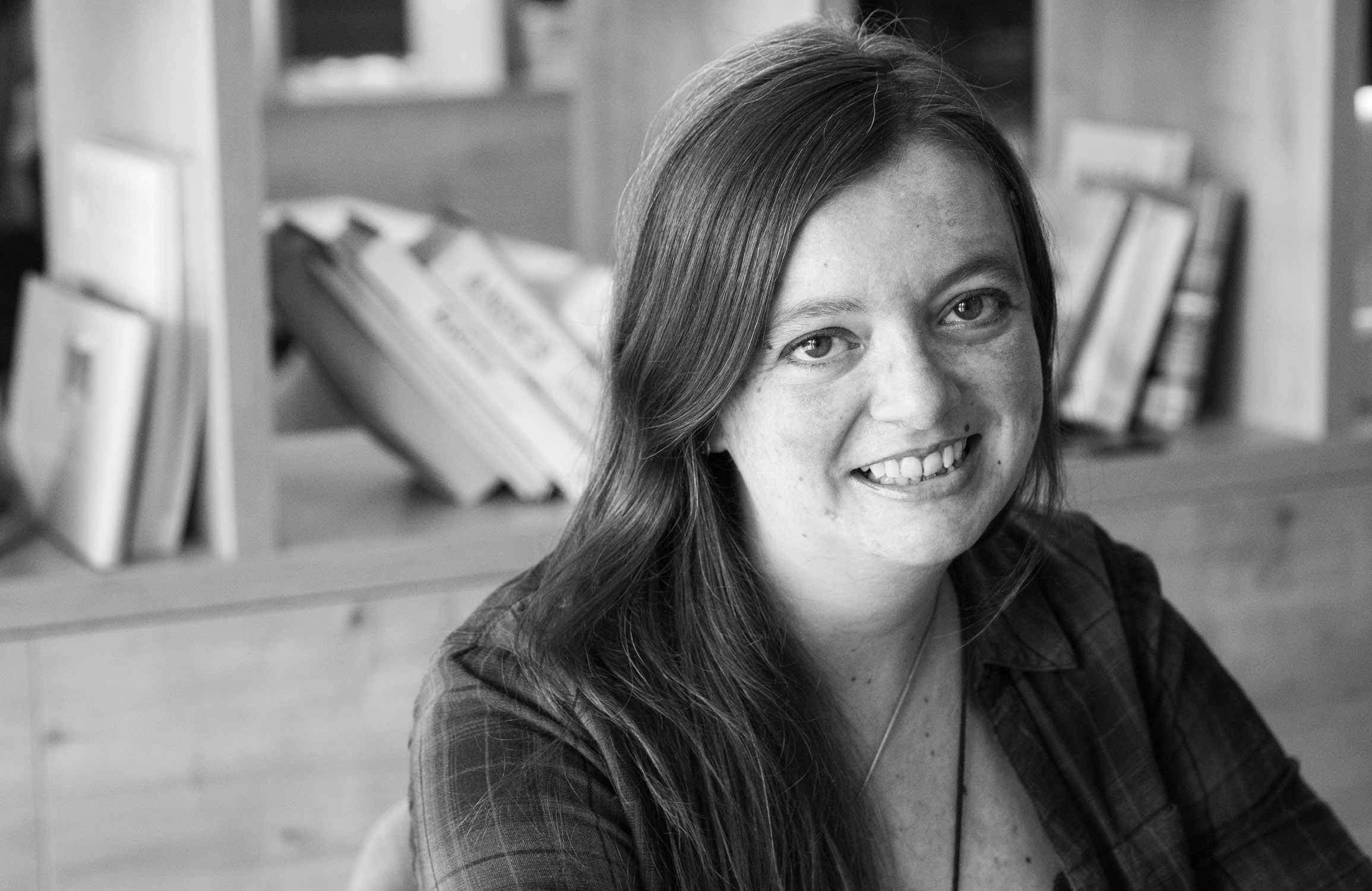 Black and white photo of author Scarlett Evans sitting in front of a bookshelf